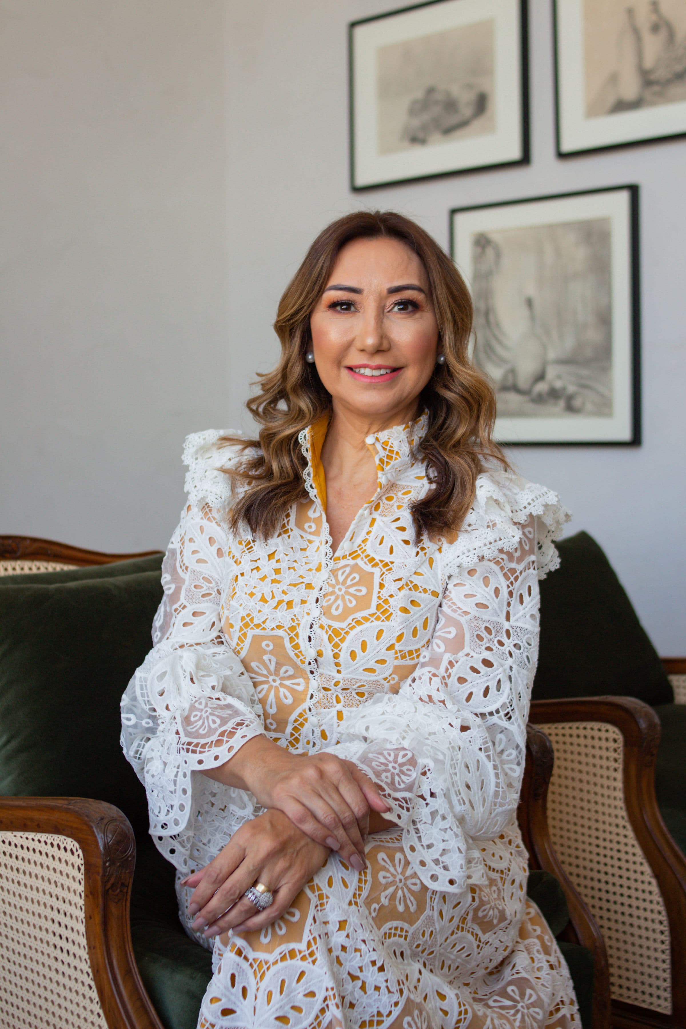 Carina Verdinelli sorrindo, sentada em uma poltrona de sua casa