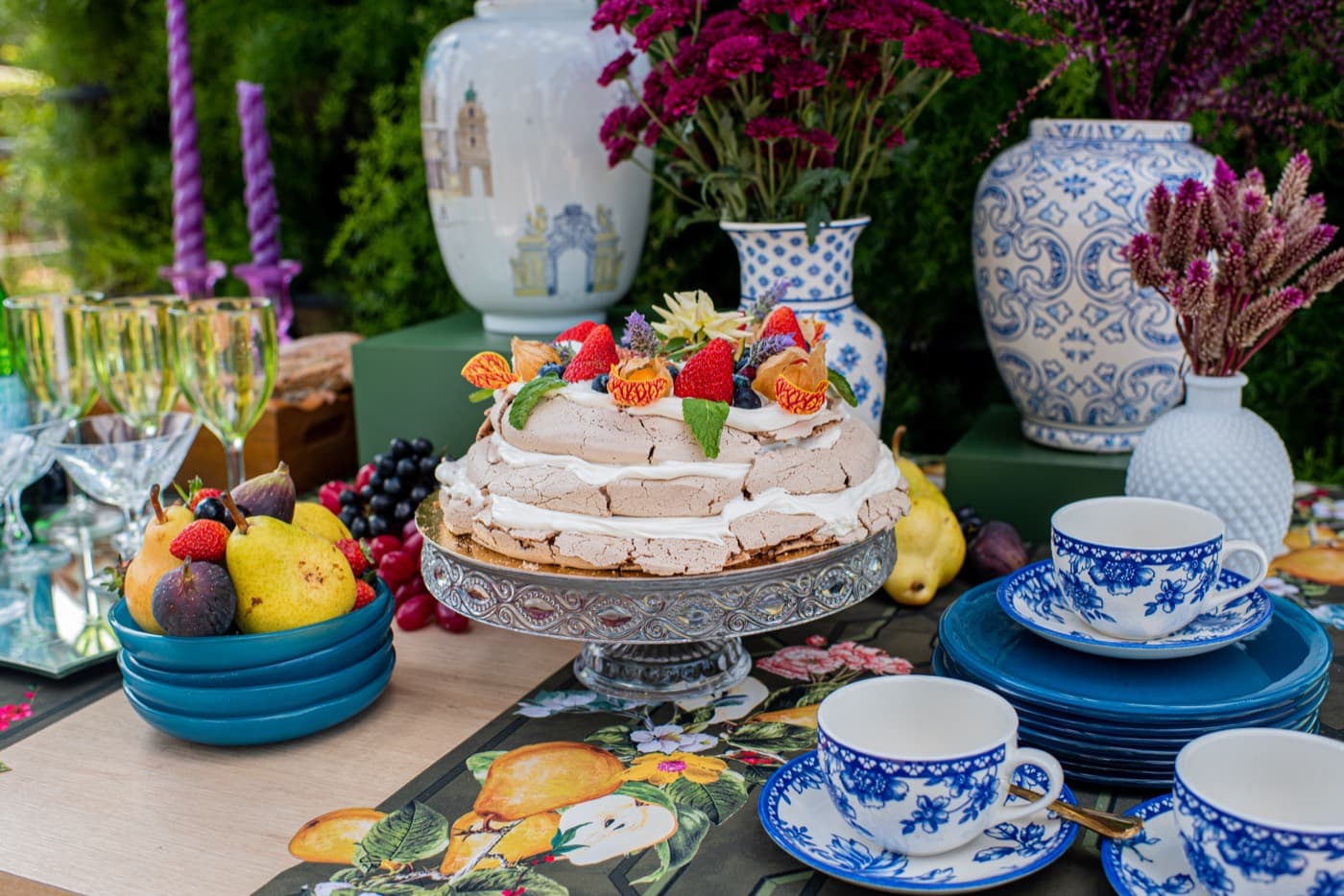 Mesa de celebração ao ar livre com pavlova, frutas e porcelana azul e branca